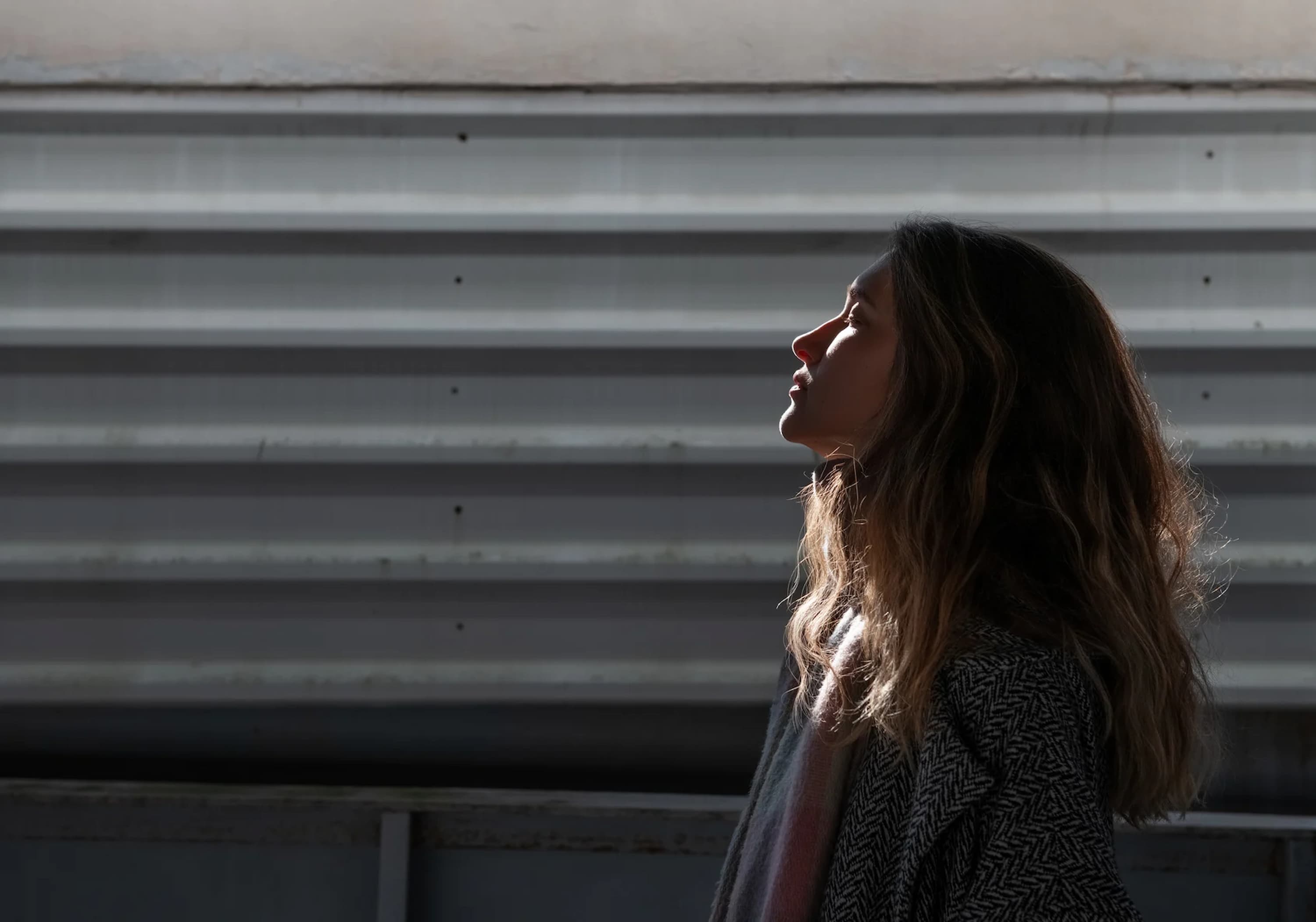 a-side-view-of-a-person-standing-in-the-shadows-in-front-of-metal-siding-learning-how-to-calm-your-mind-from-overthinking