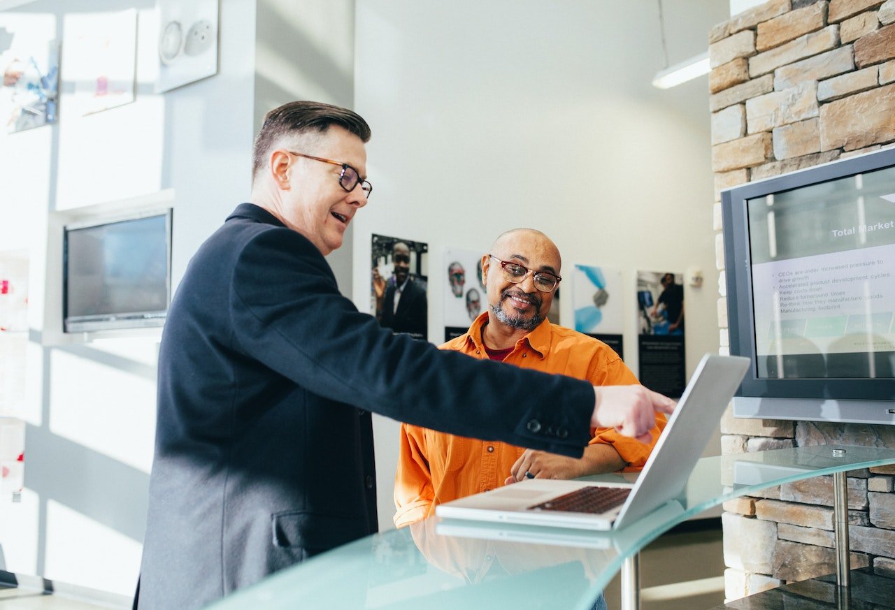 Businessman-pointing-at-computer-and-smiling-while-talking-to-client-jobs-for-extroverts