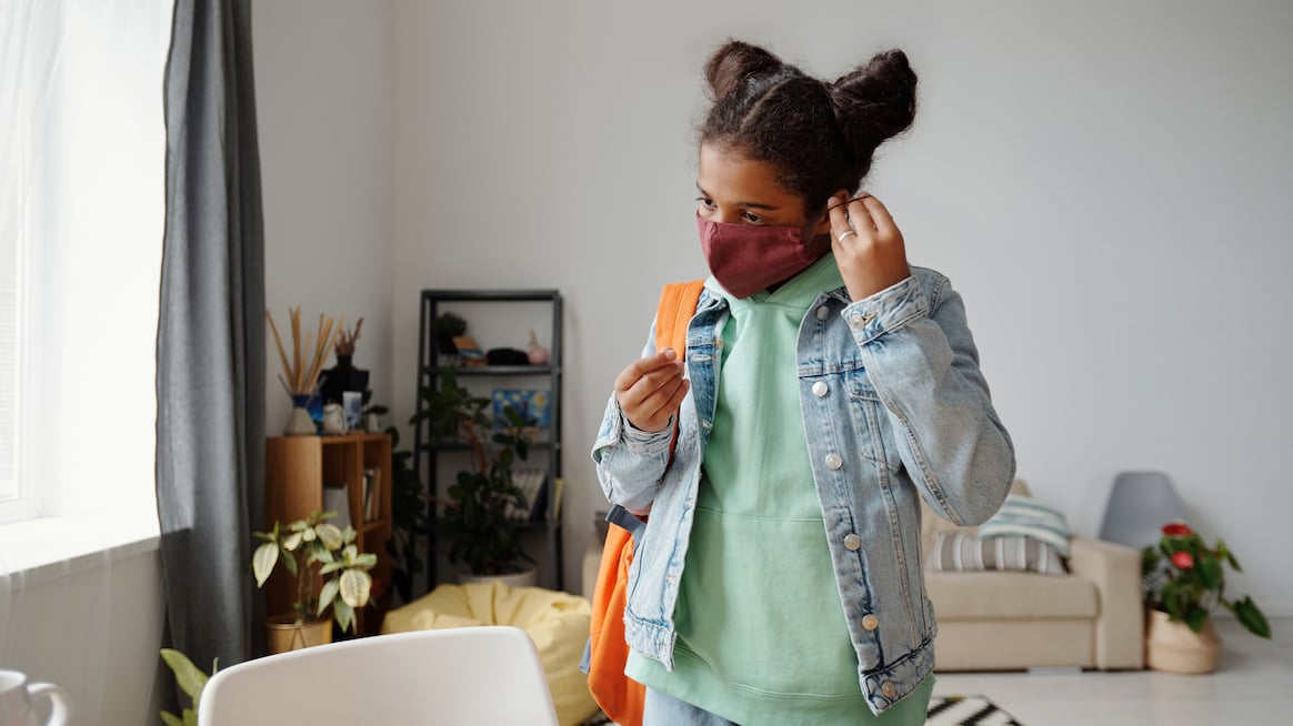 young-girl-in-mask-puts-on-backpack-for-working-parents-return-to-work-is-hard