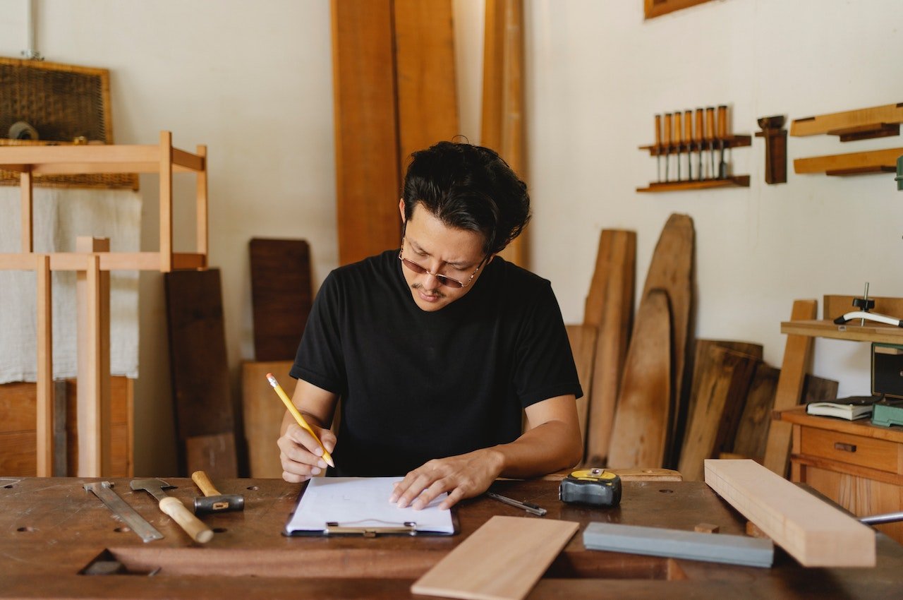 Man-on-art-studio-writing-on-paper-with-tools-on-table-beside-him-10-year-plan-examples