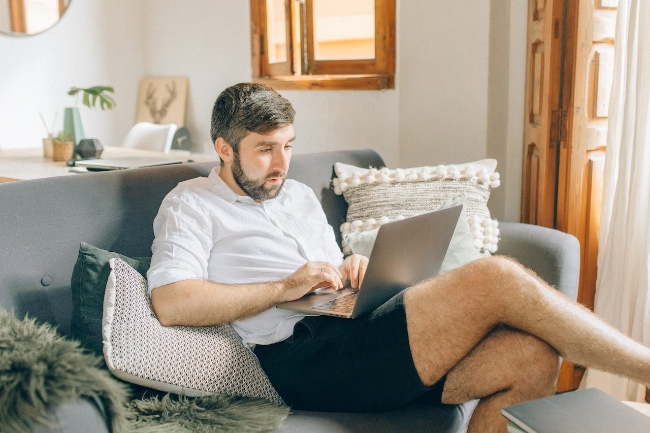 Man-sitting-on-his-couch-using-his-work-laptop-salary-negotiation-email