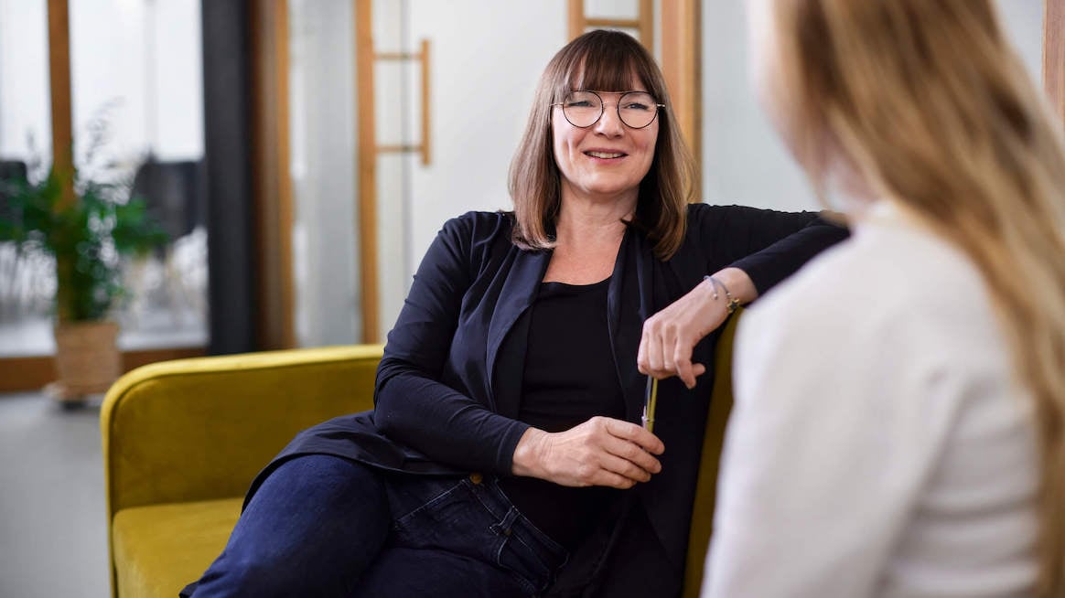 performance-review-questions-woman-talking-to-colleague-on-couch