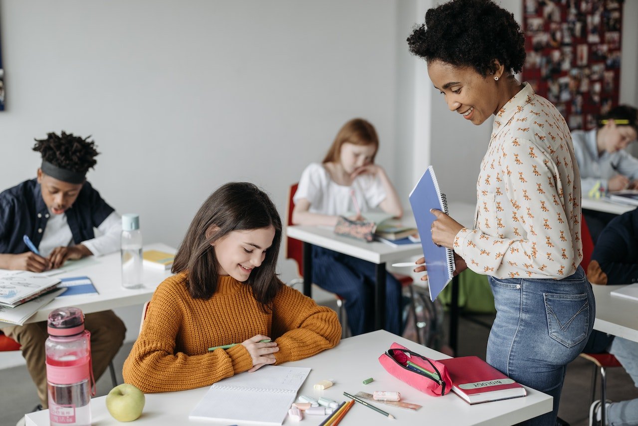 teacher-looking-at-students-notebook-smiling-teacher-career-coach