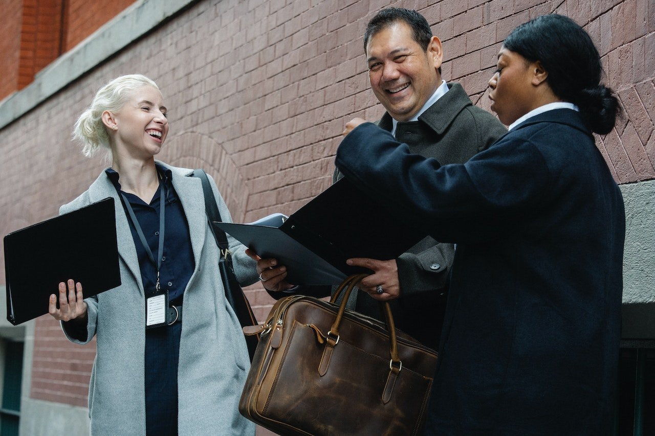 three-coworkers-smiling-and-greeting-each-other-outside-office-professional-coaching
