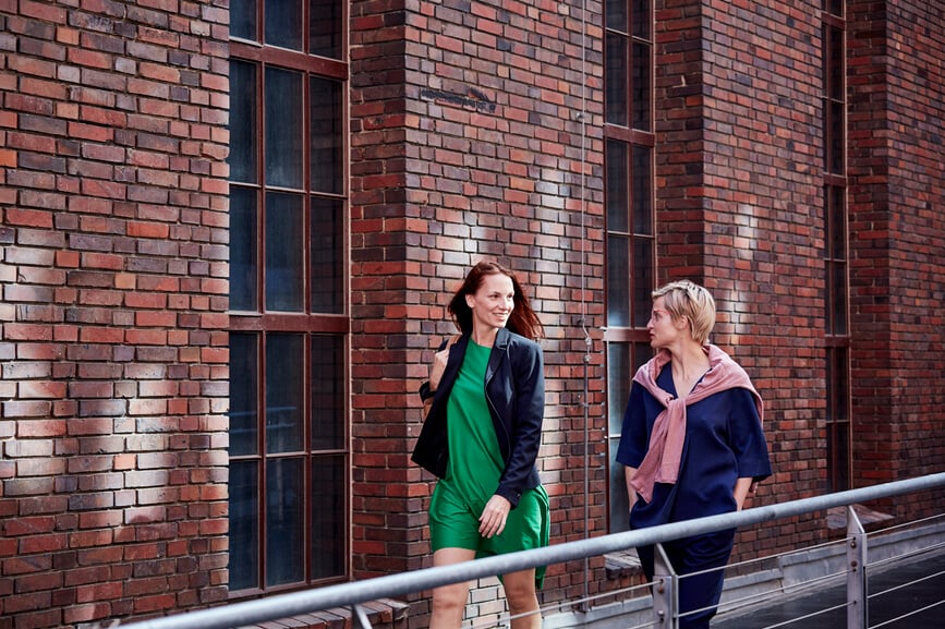 two-female-colleagues-walking-outside-building-reverse-mentoring