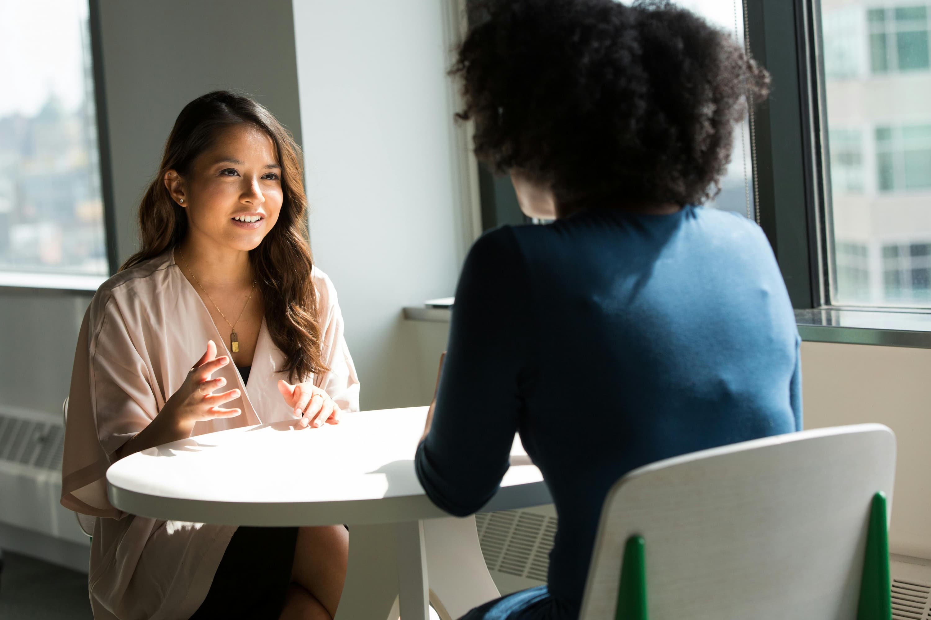 two-people-talking-sitting-at-a-small-white-table-discussing-types-of-listening