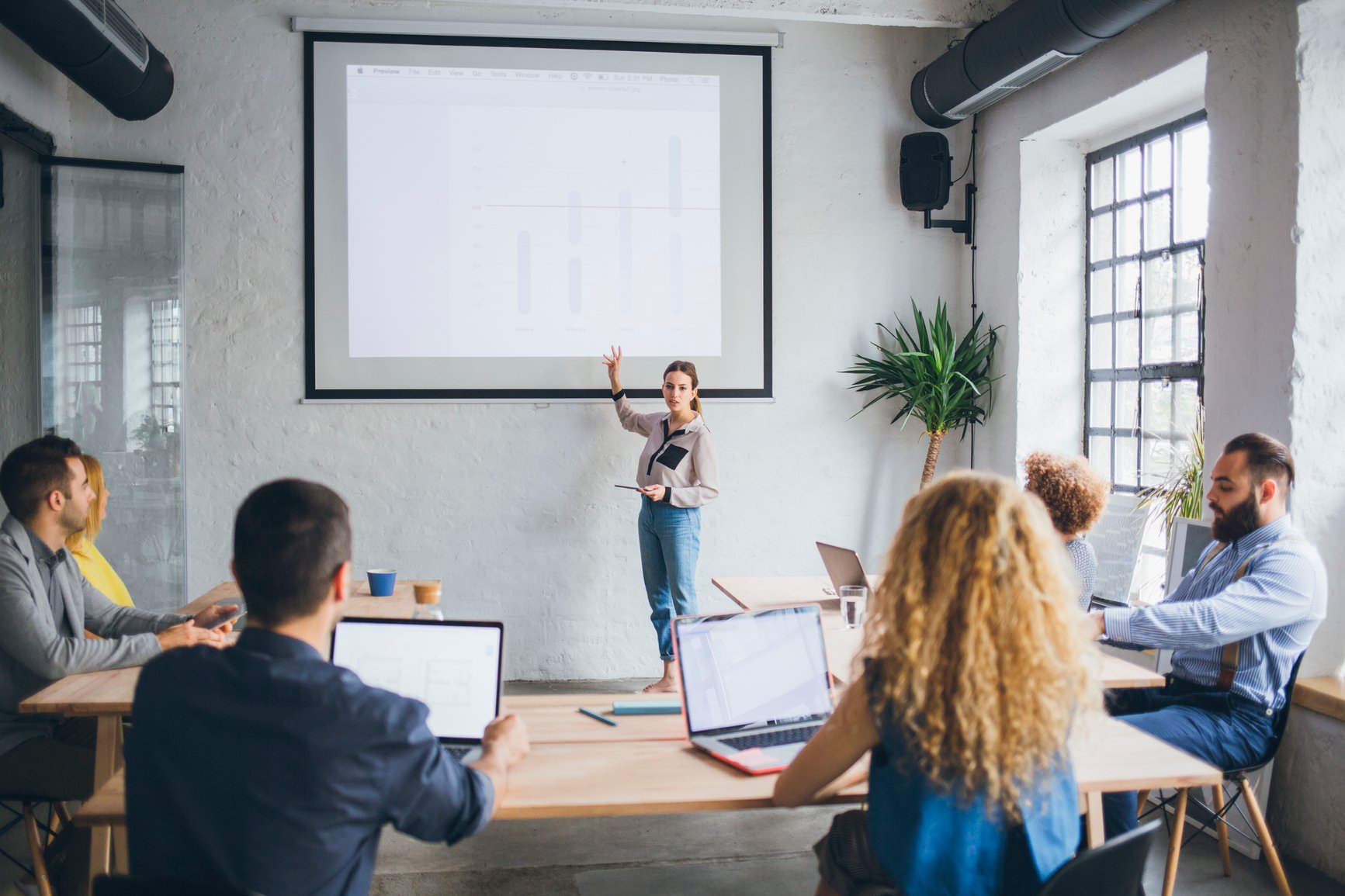 small-woman-presents-confidently-in-front-of-large-screen-how-to-give-a-good-presentation